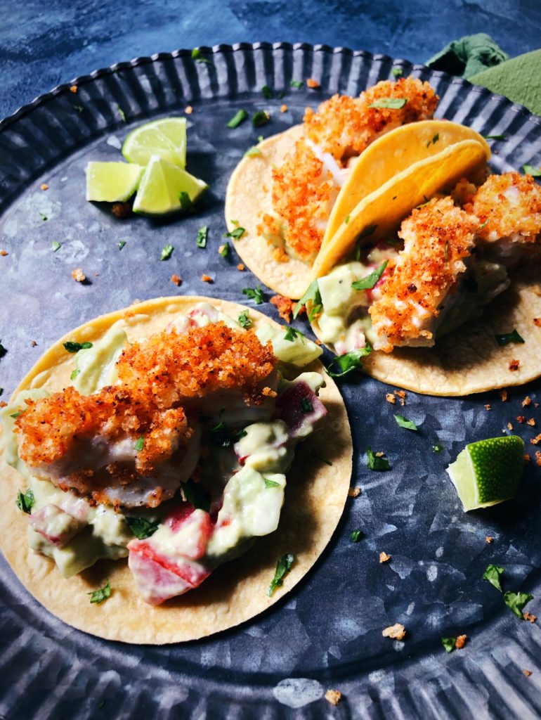 three breaded cod tacos on a round metal platter