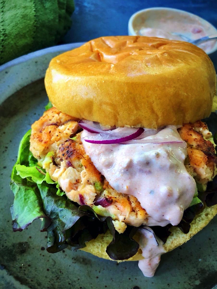 salmon burger with bun and lettuce and creamy pink sauce