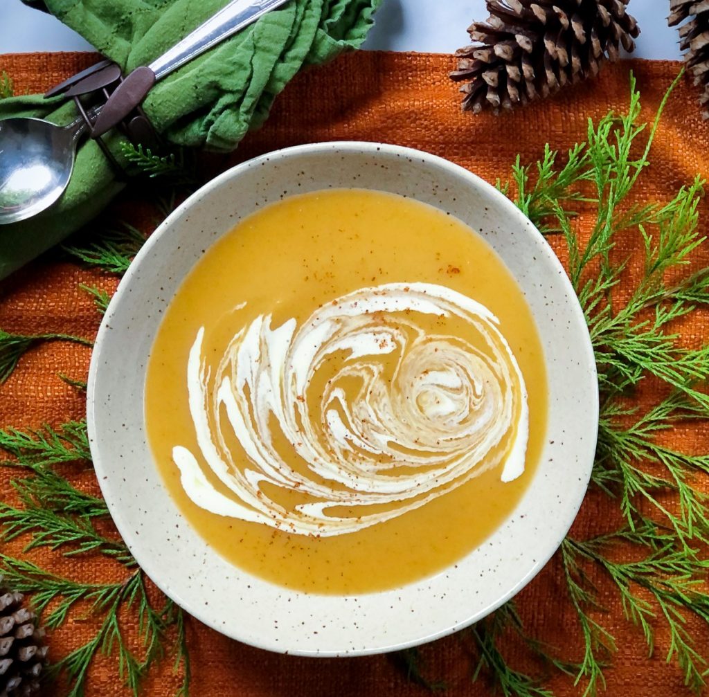 butternut squash bisque on an orange placemat with pine cones and pine